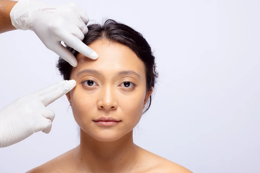 A doctor who wear medical glove that do a face lift checked on women face which after help her do facial lifting treatment.